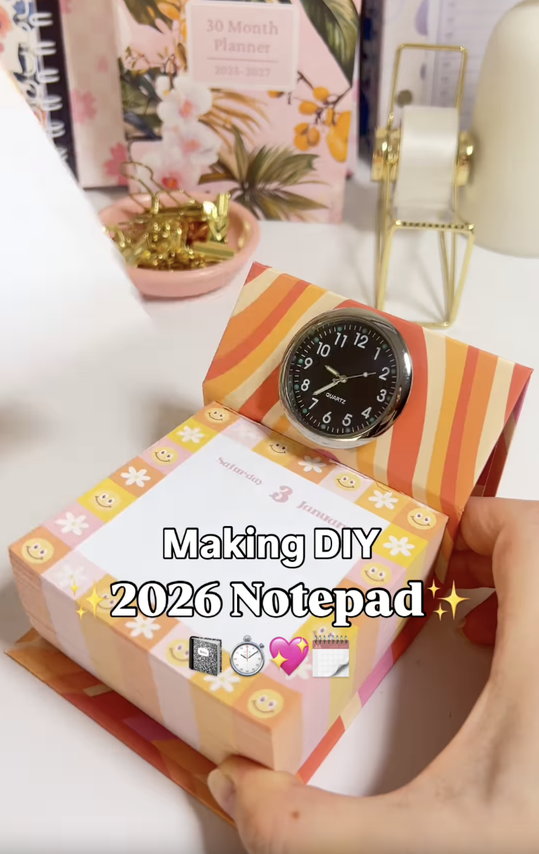 Finished DIY notepad inside a four-panel folding chipboard cover with a small clock on the headboard
